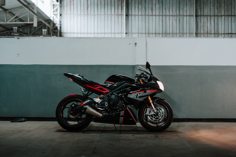 black and red sports bike parked beside white wall