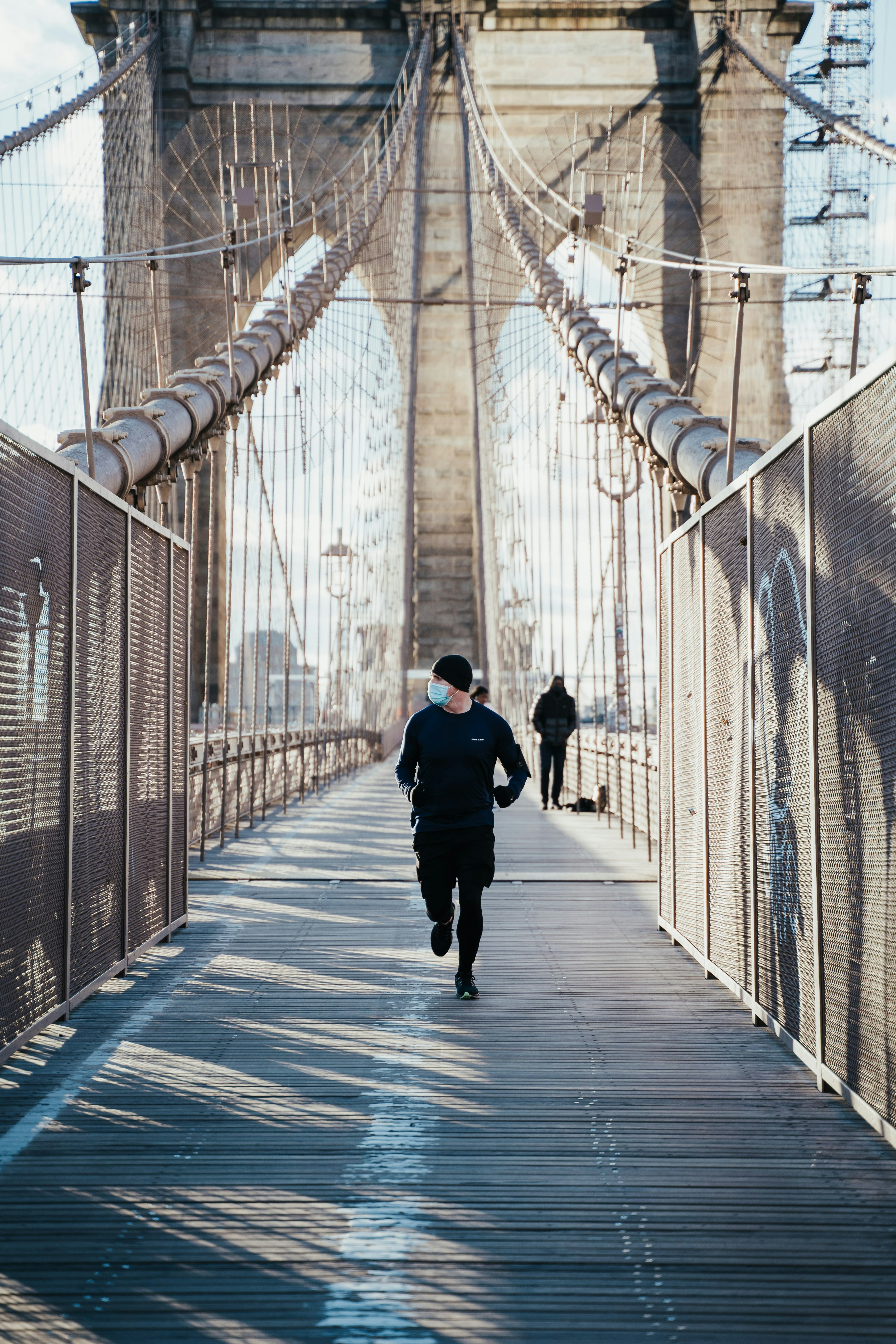 man in black jacket walking on bridge during daytime