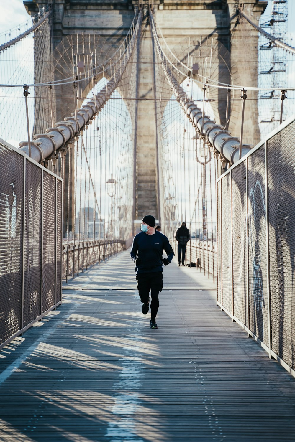 man in black jacket walking on bridge during daytime
