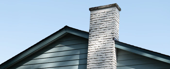 Brick chimney and roofline against a cloudy sky