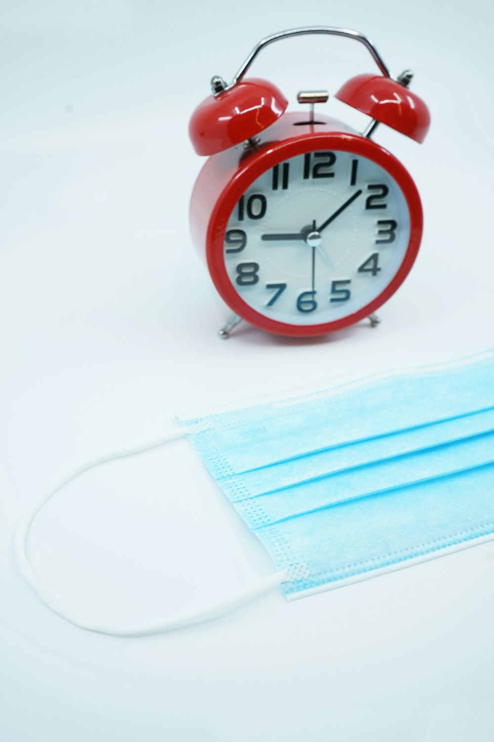 red and white analog alarm clock at 10 10