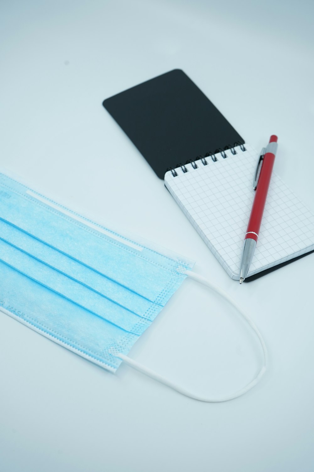 red and white click pen on white notebook