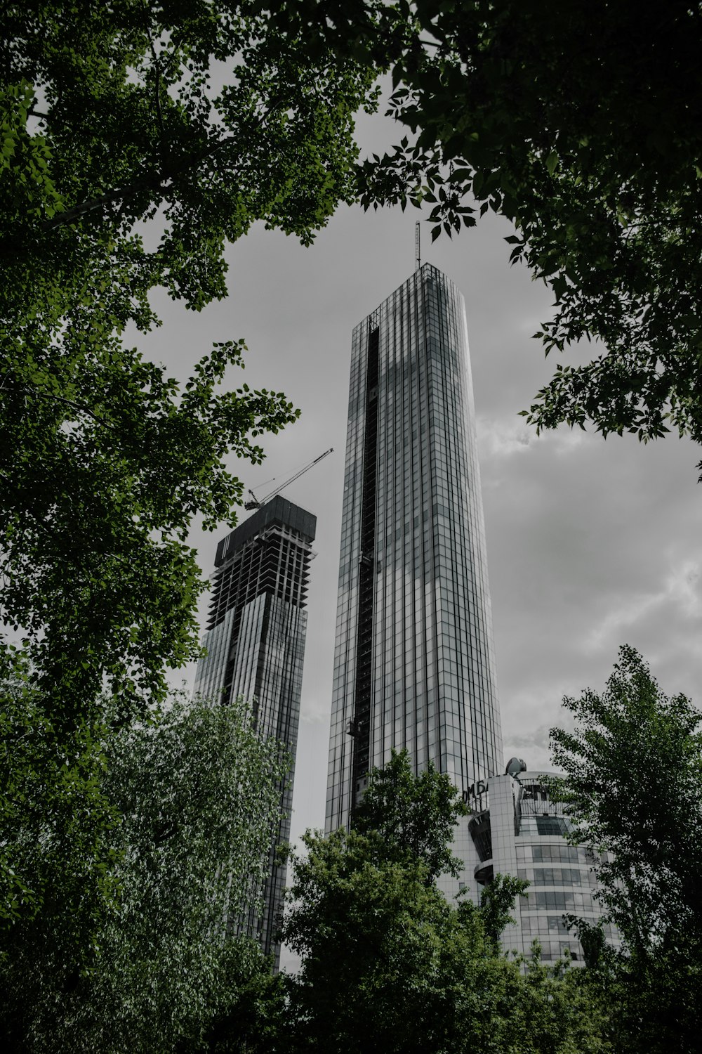 gray concrete building near green trees under white clouds during daytime