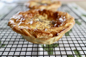 Close-up of a golden crusted apple pie cooling on a wooden rack
