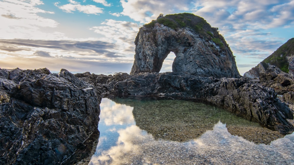 gray rock formation on body of water under blue sky during daytime