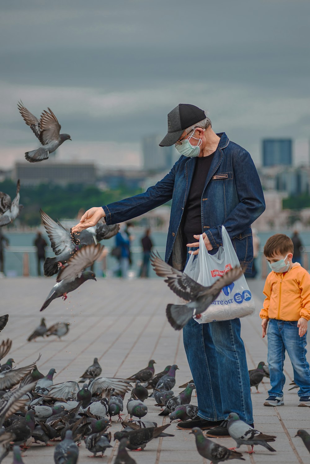 man in blue jacket and orange cap holding a baby in orange jacket