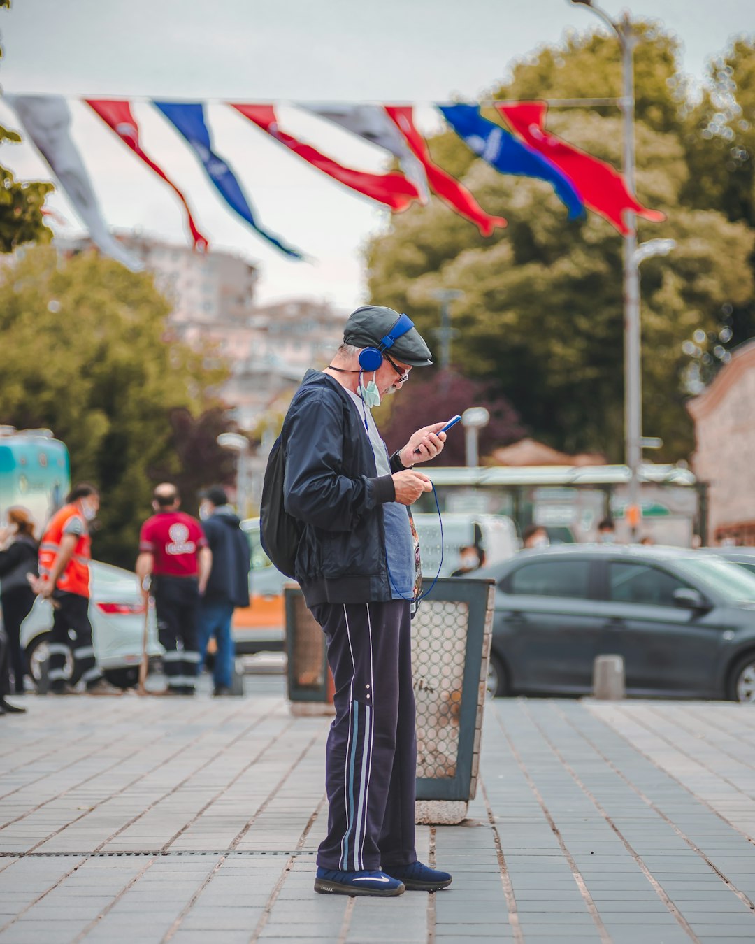 man in black jacket and black and white pants standing on sidewalk during daytime