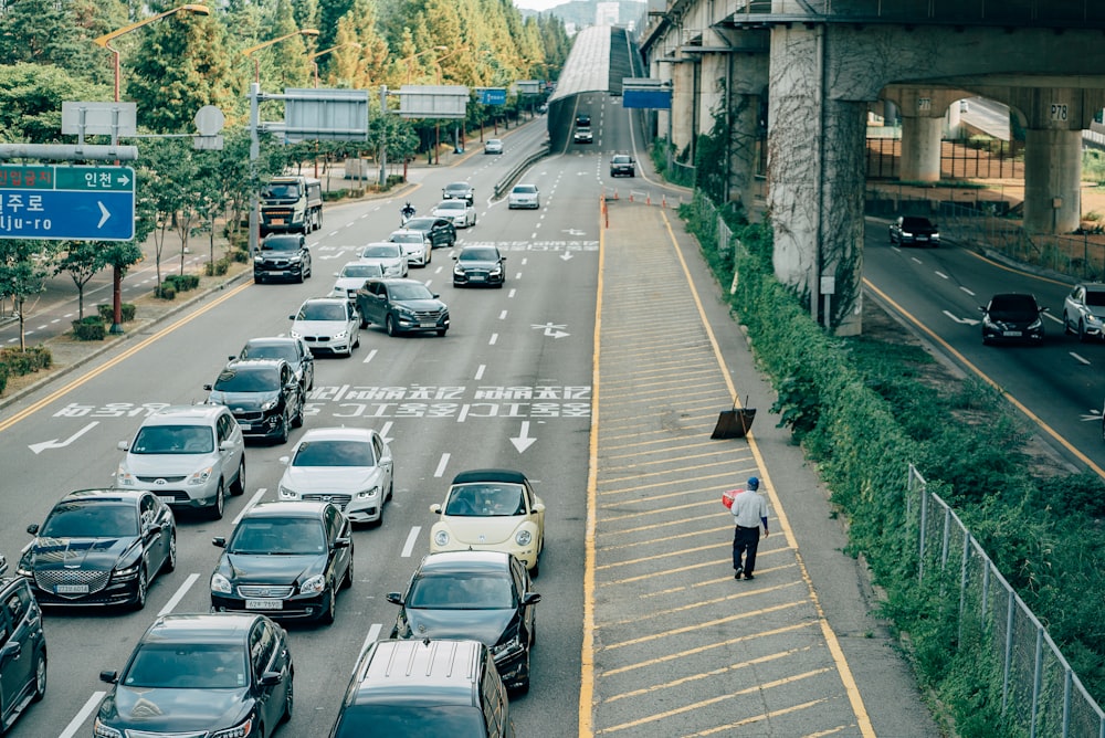 people walking on sidewalk with cars parked on side of the road during daytime