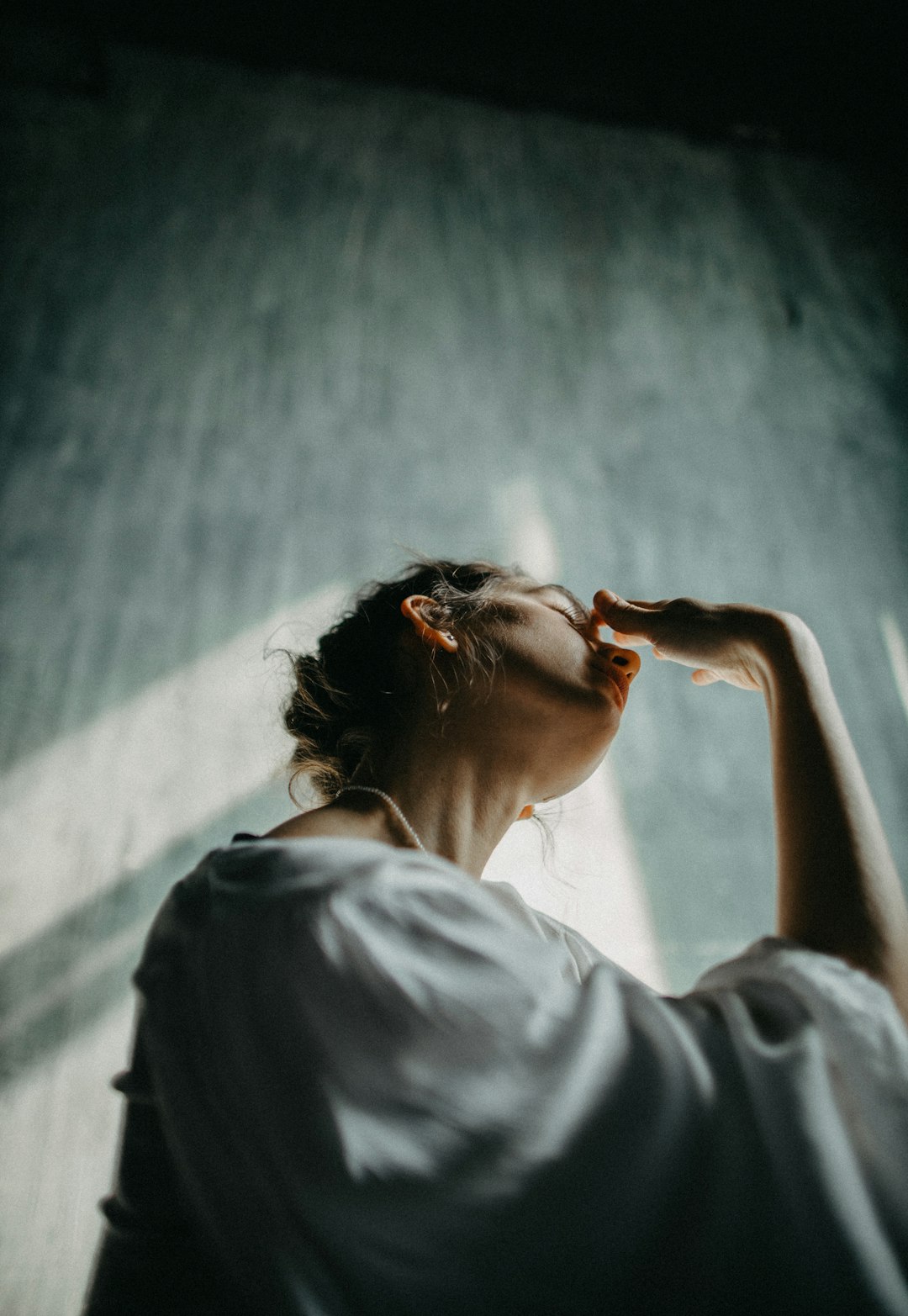 woman in white shirt covering her face with her hands