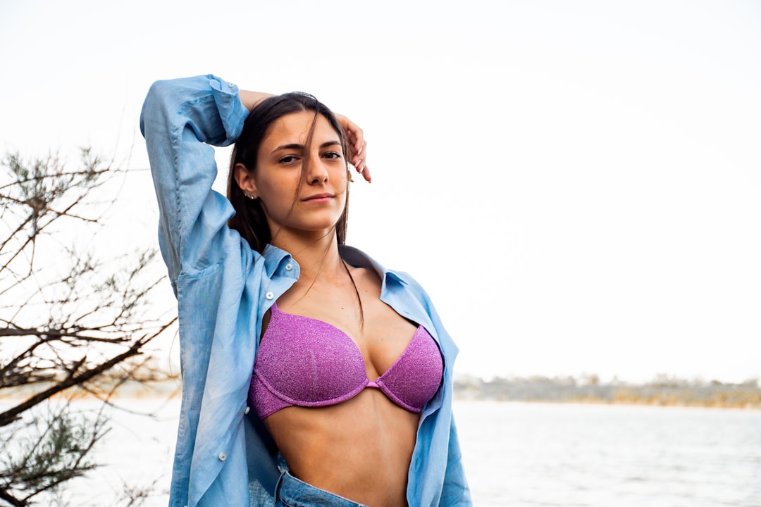 woman in blue bra and blue denim jeans standing on beach during daytime