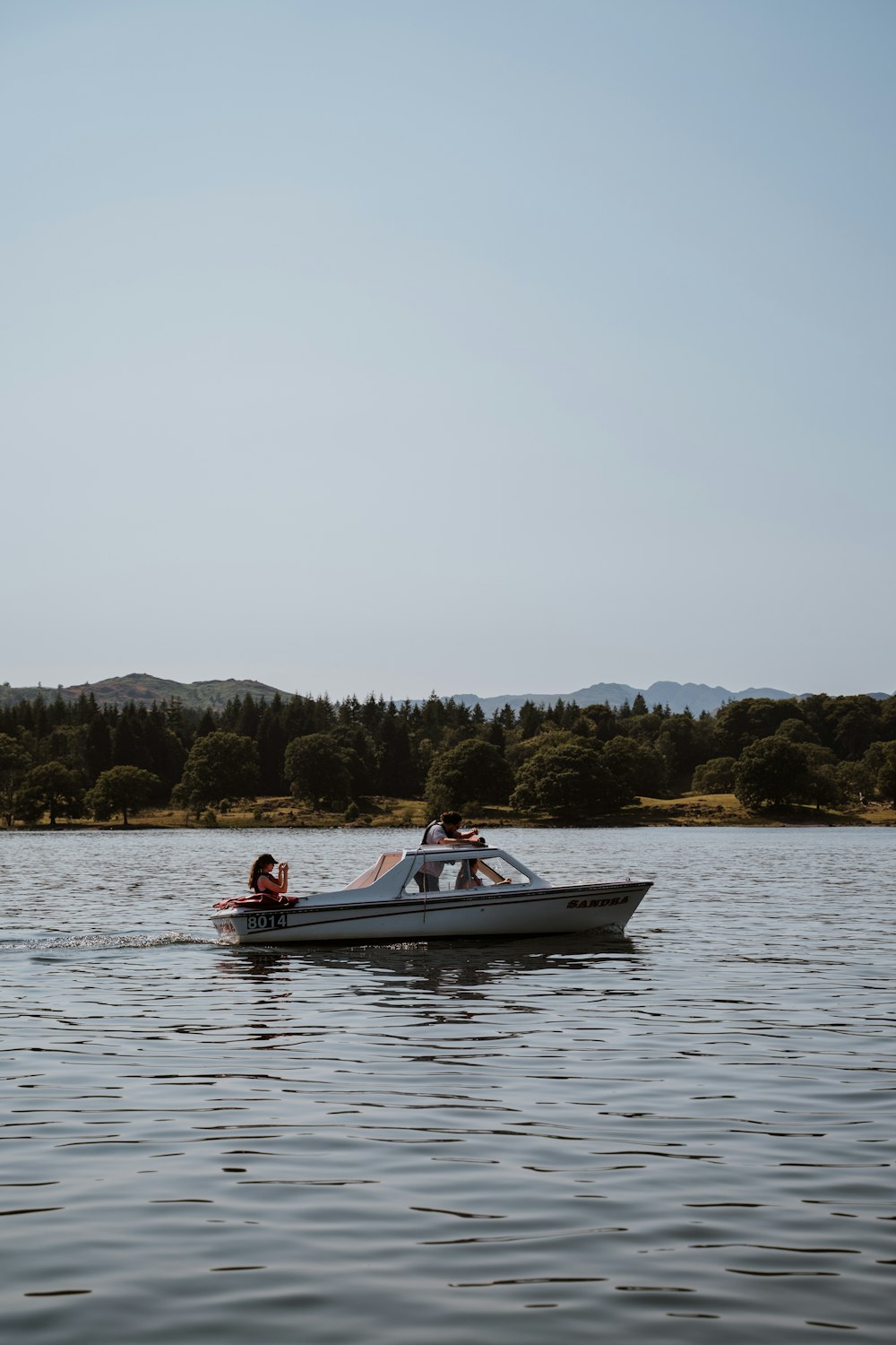 2 people riding on red and white boat on lake during daytime