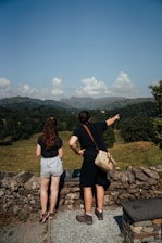 2 women standing on gray rock near green grass field during daytime