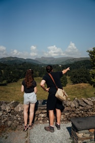 2 women standing on gray rock near green grass field during daytime