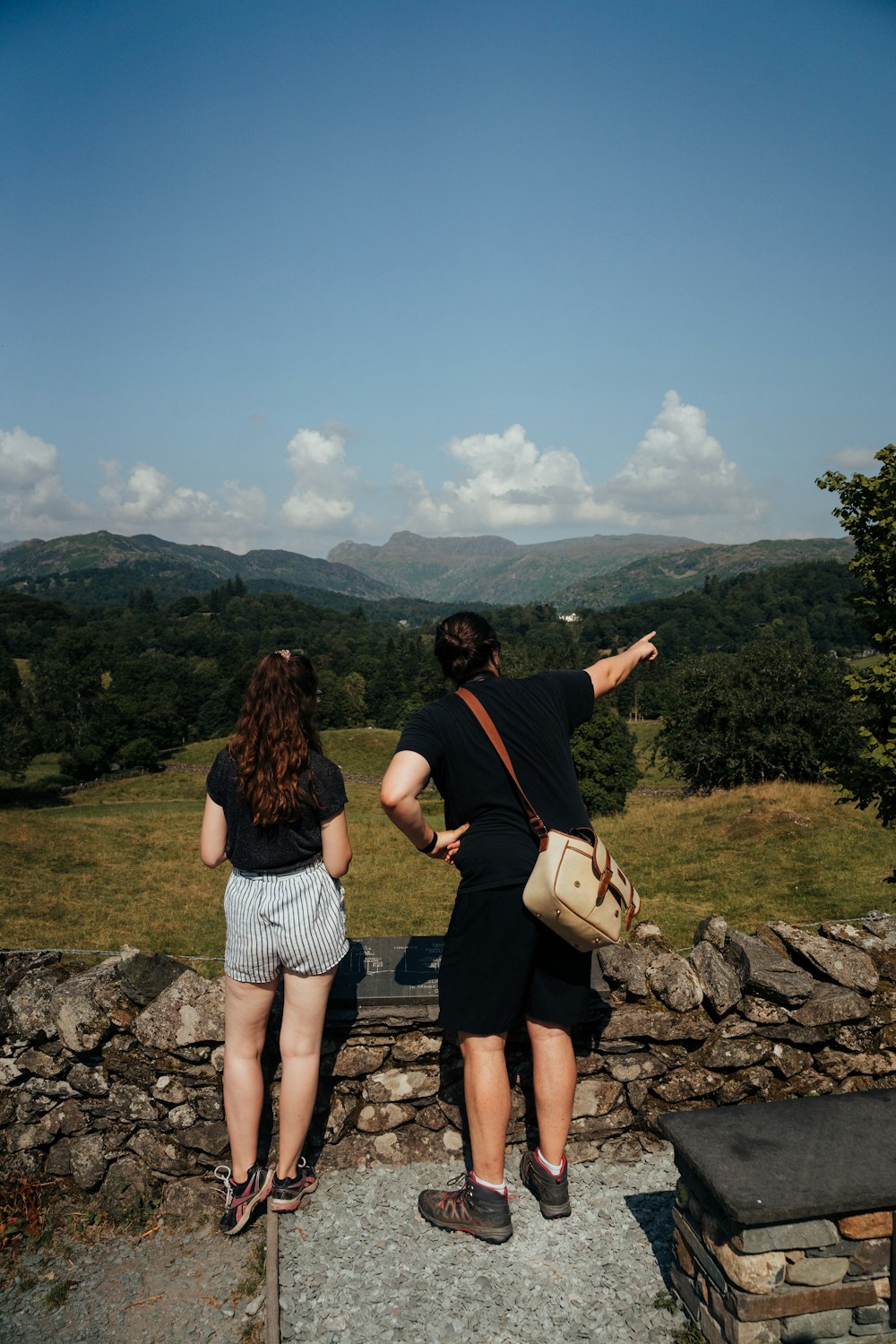 2 women standing on gray rock near green grass field during daytime