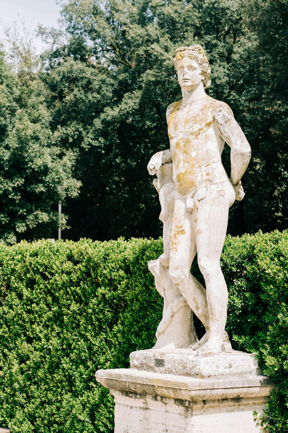 woman statue near green trees during daytime