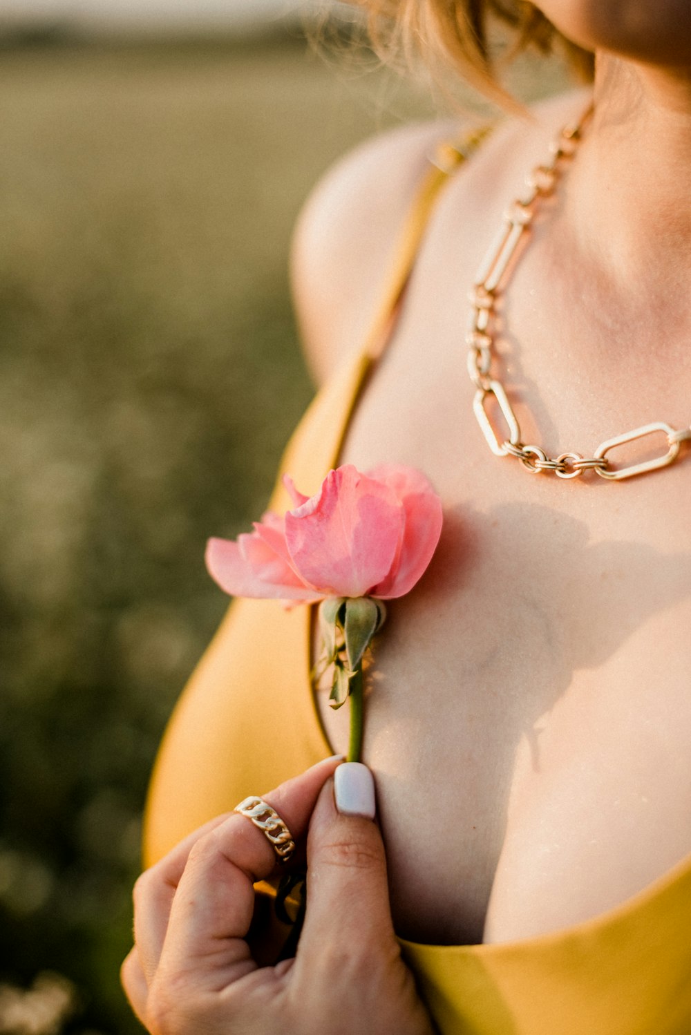 woman in gold necklace with pink rose on her body
