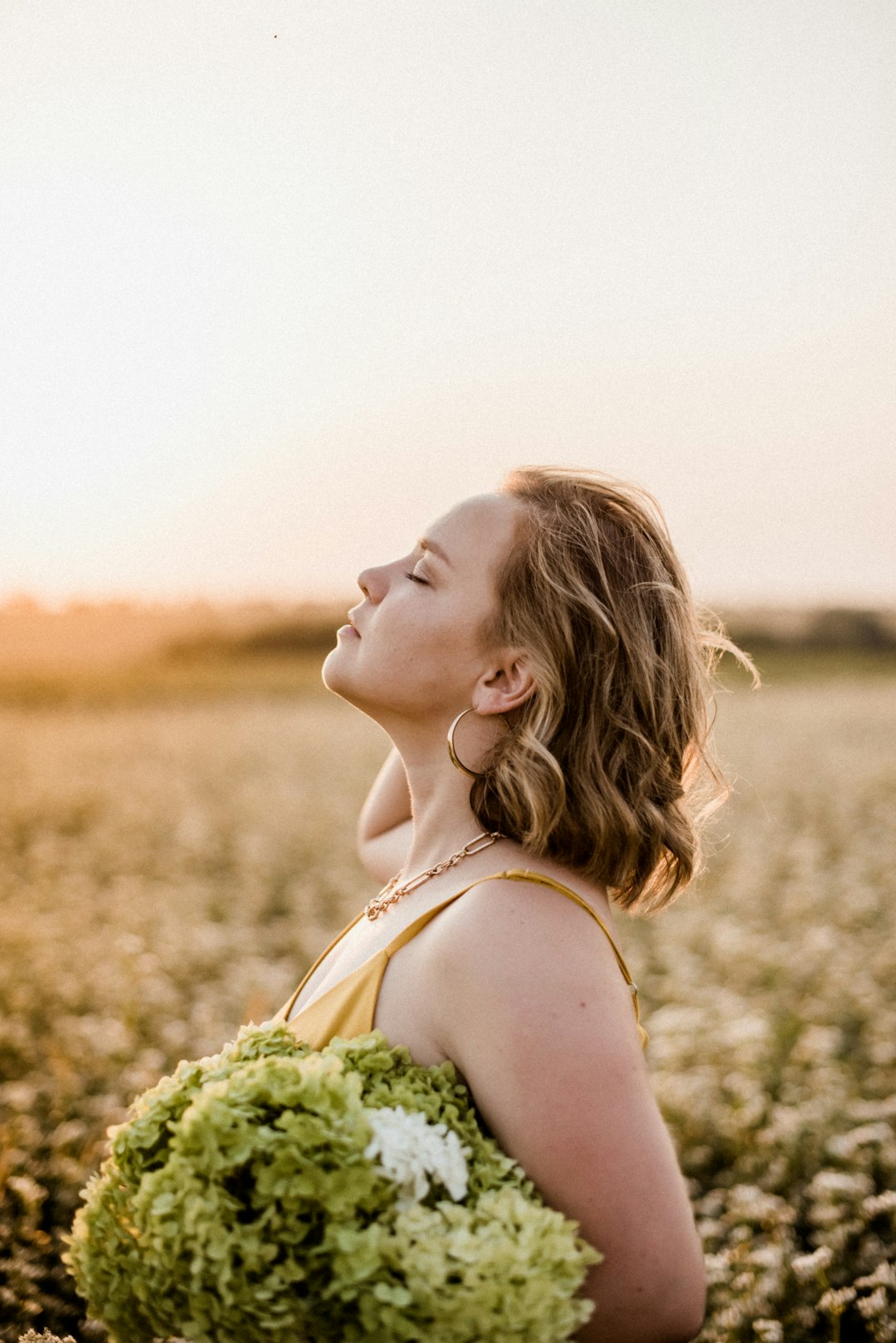 woman in white tank top holding bouquet of flowers