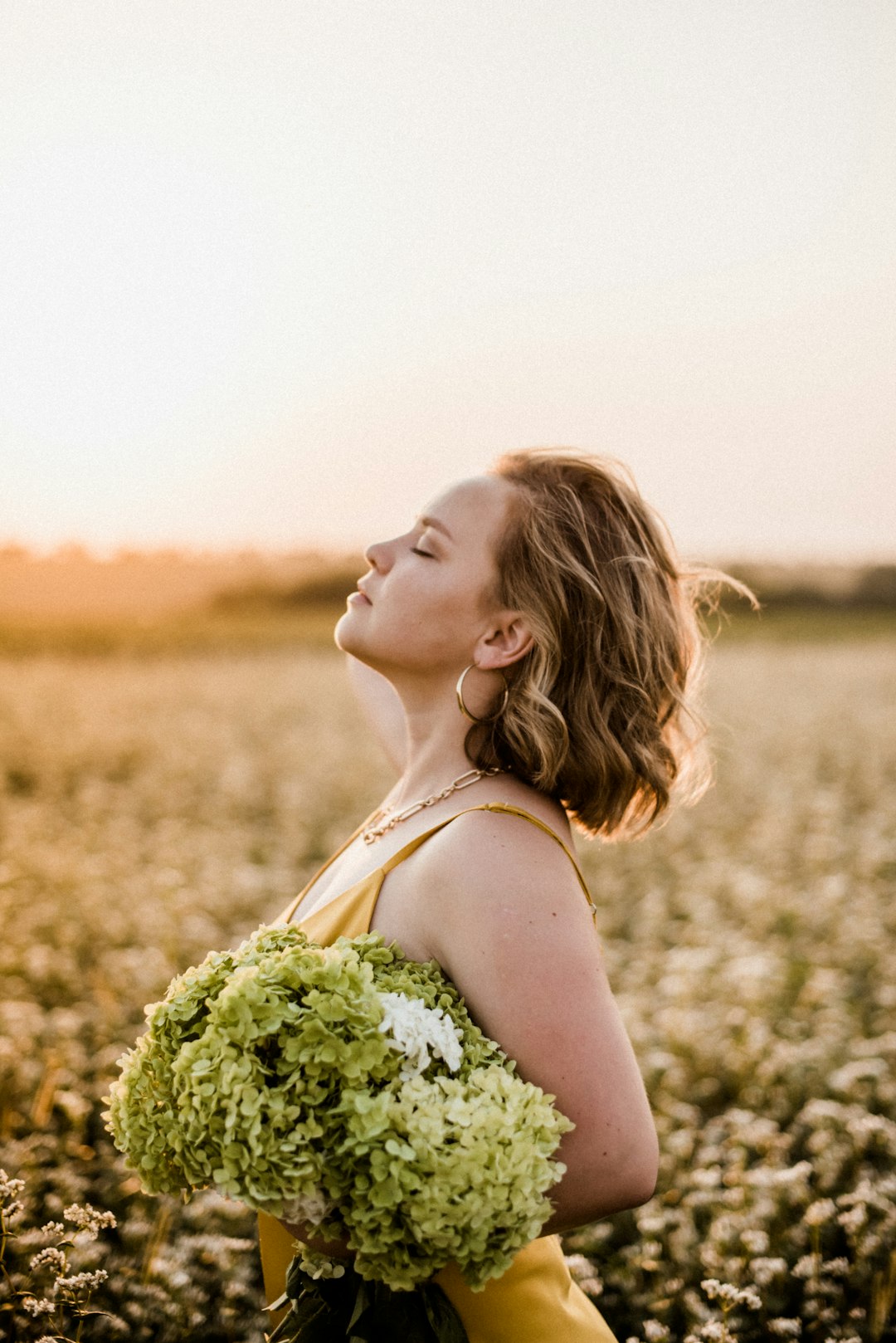 woman in white tank top holding bouquet of flowers