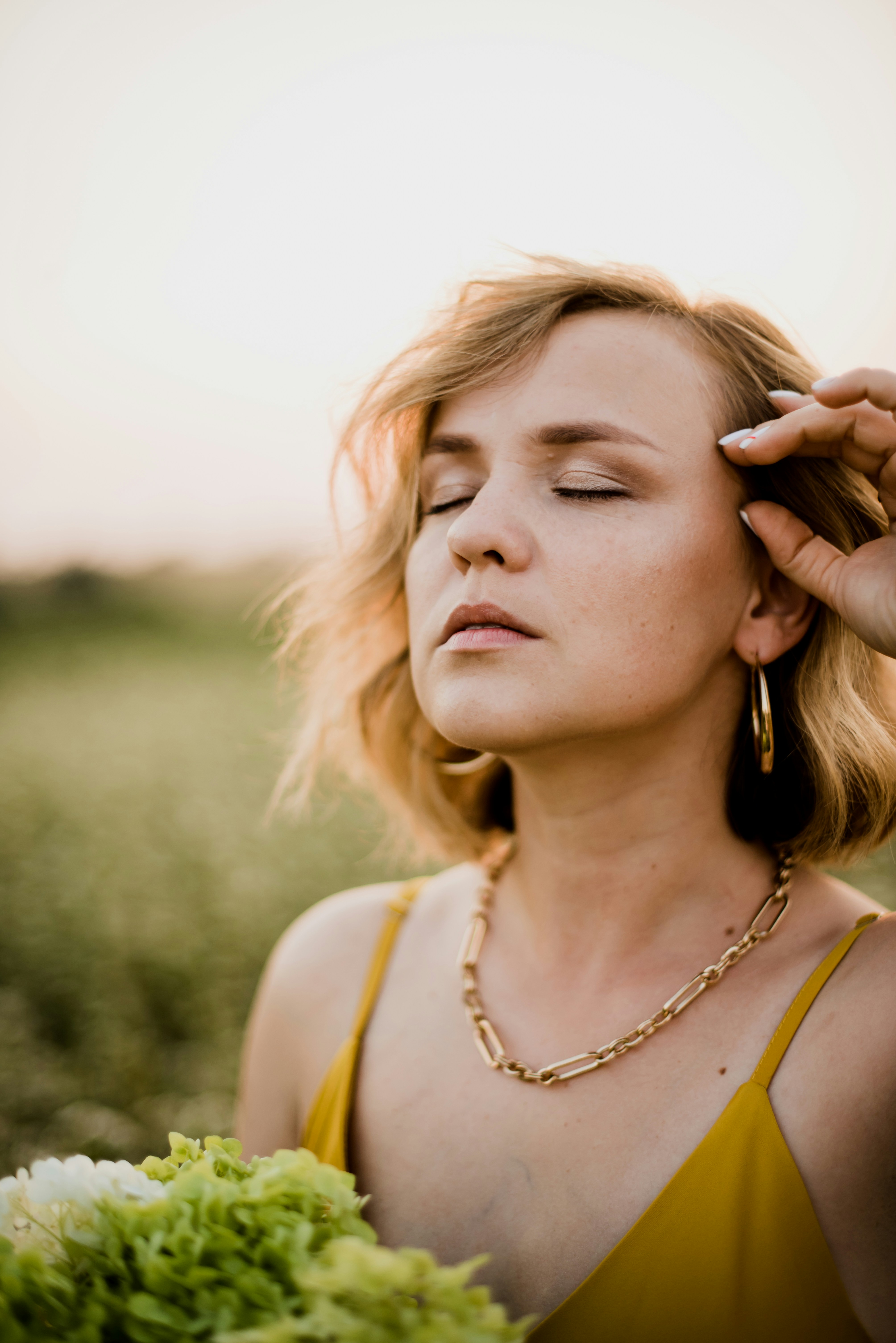 woman in yellow tank top holding her hair