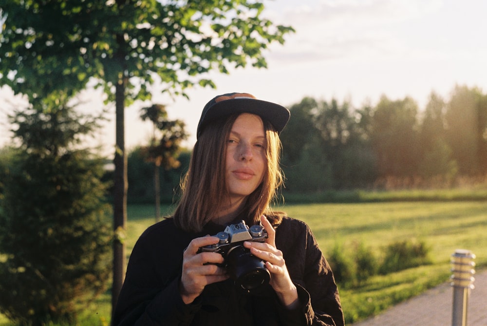 woman in black hat holding black smartphone