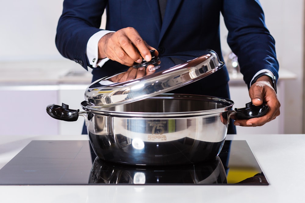 person in blue blazer holding stainless steel cooking pot