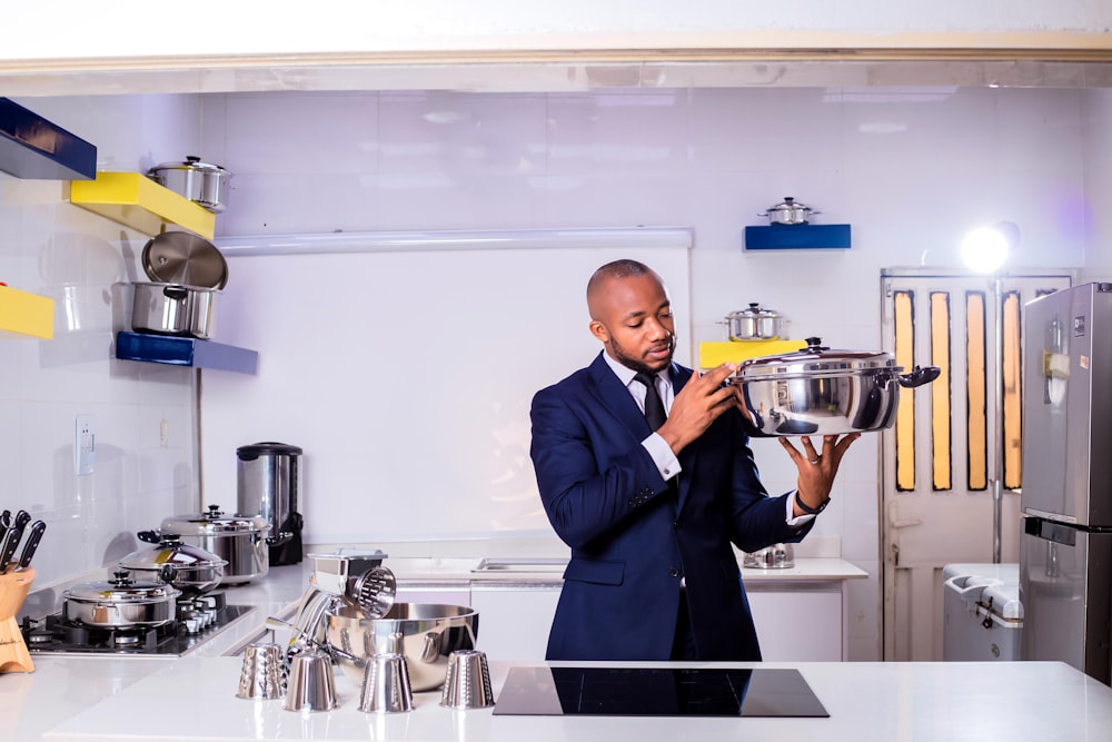 man in black suit holding stainless steel cooking pot