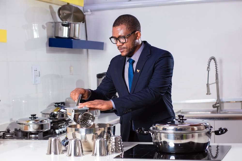 man in black suit jacket holding stainless steel cooking pot