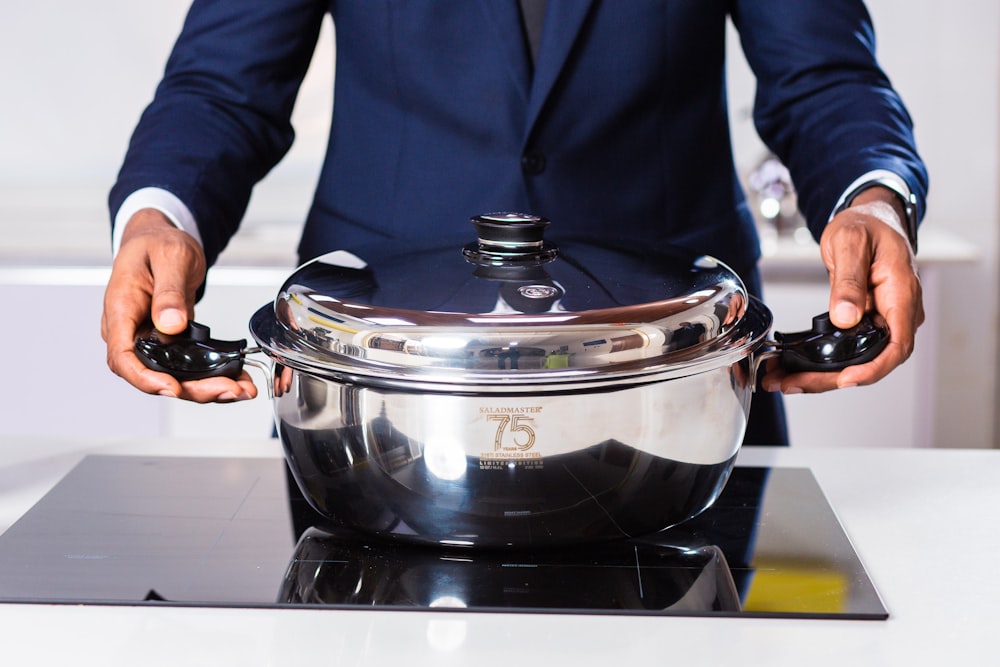 person in blue blazer holding black and silver slow cooker