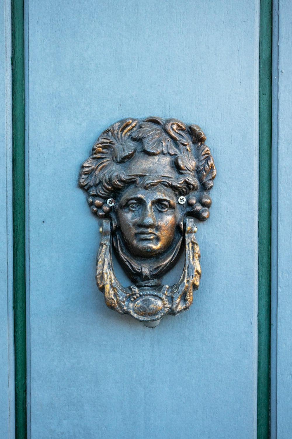 Busto de la cabeza del león dorado en la puerta de madera azul