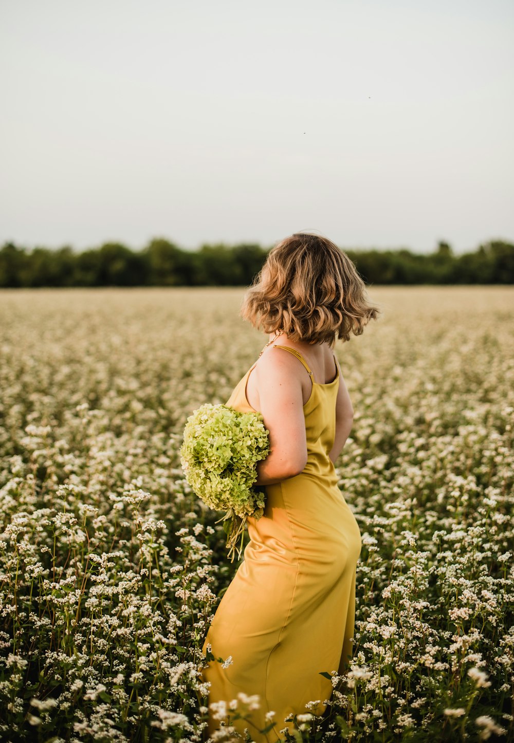 woman in yellow sleeveless dress holding yellow flower bouquet