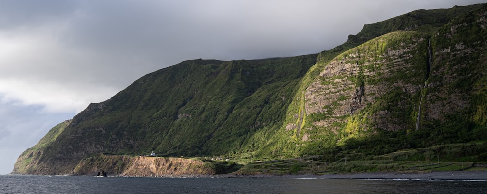 green mountain beside body of water during daytime