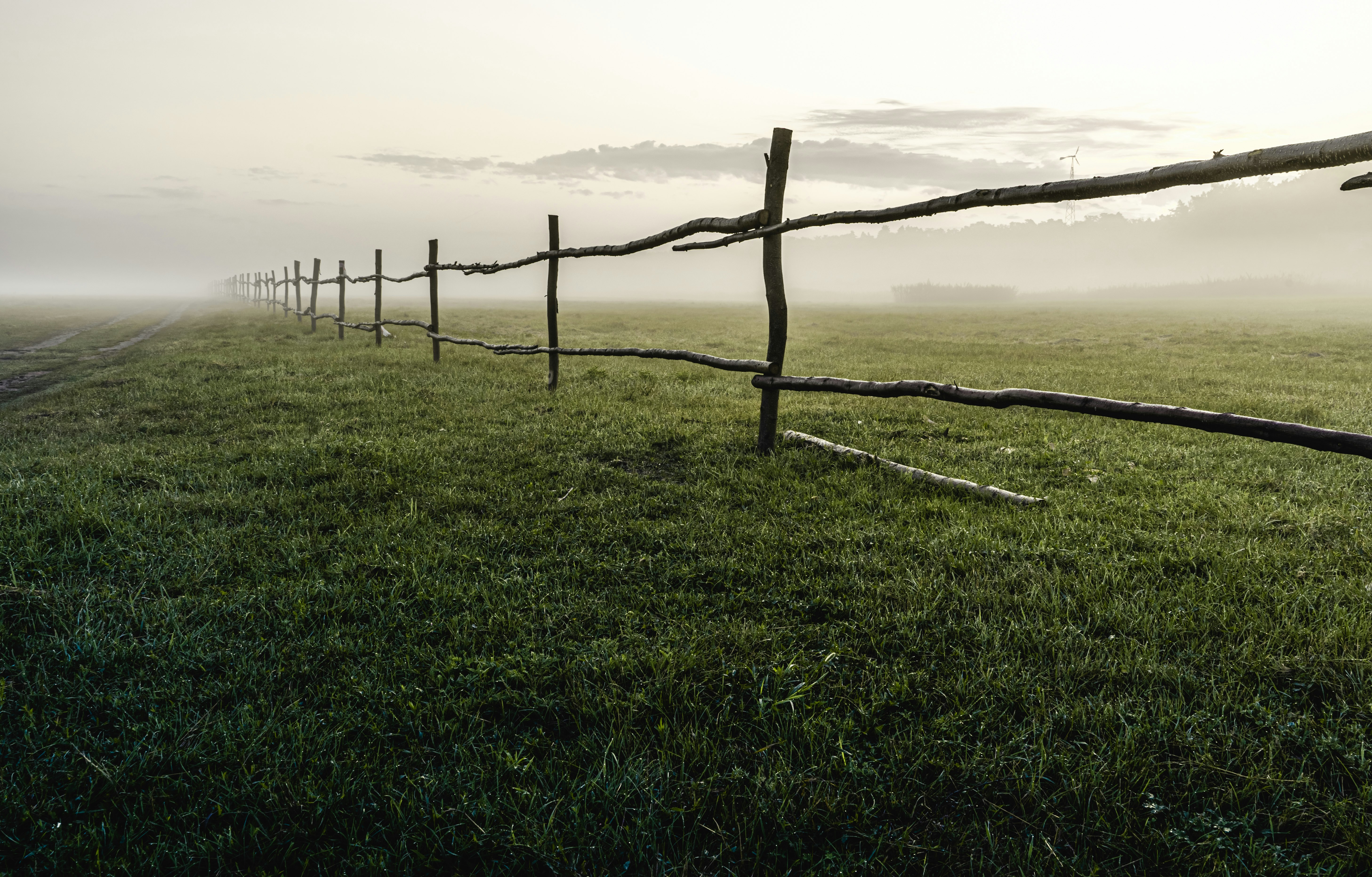 brown wooden fence on green grass field during daytime
