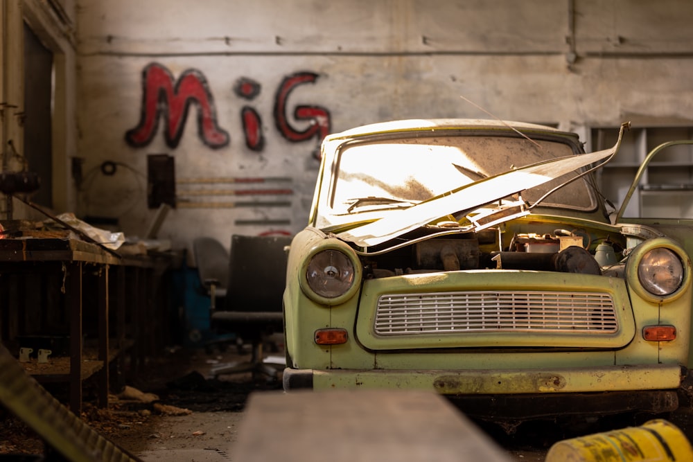 white and green vintage car parked beside white wall