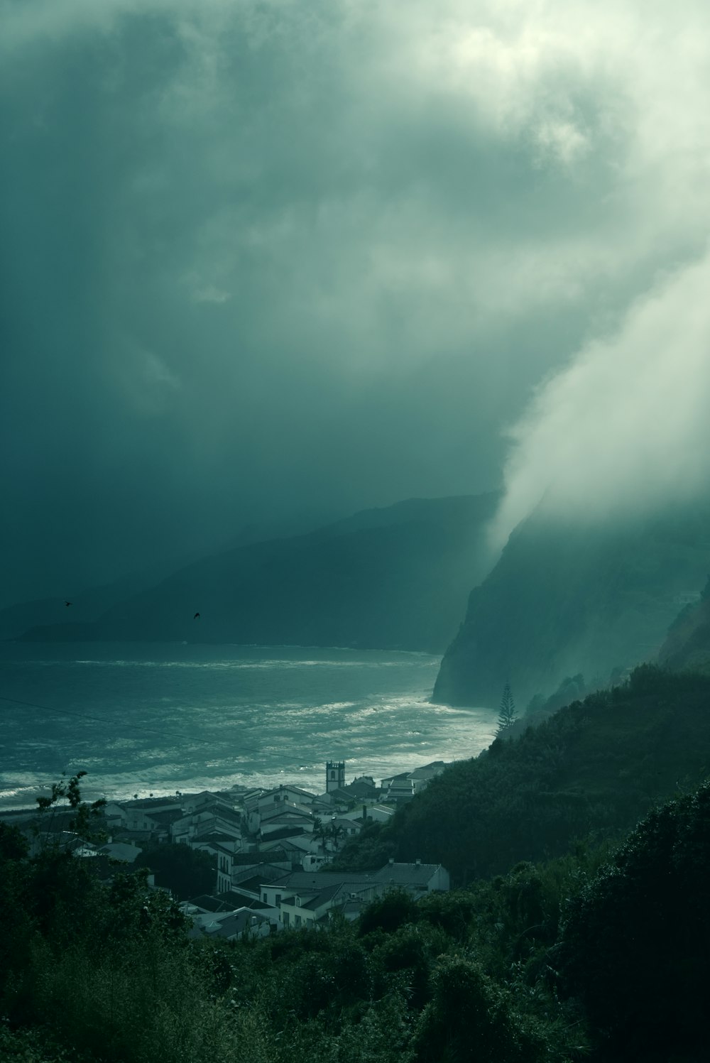 ocean waves crashing on rocks under white clouds during daytime