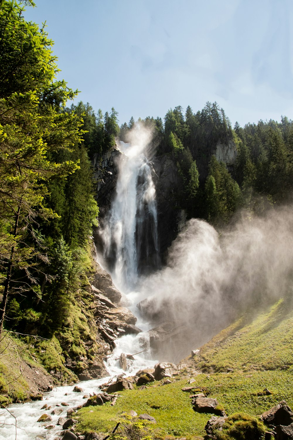 waterfalls in the middle of green trees under blue sky during daytime