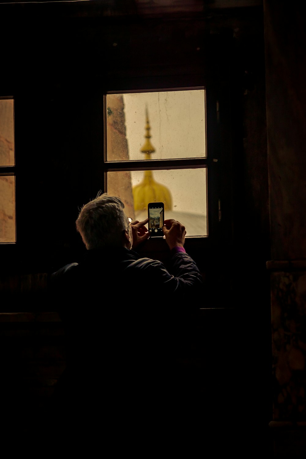 man in black jacket sitting on window during daytime