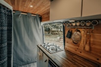 Eliana and Hernán cooking together inside their pastel green and gray motorhome kitchen.