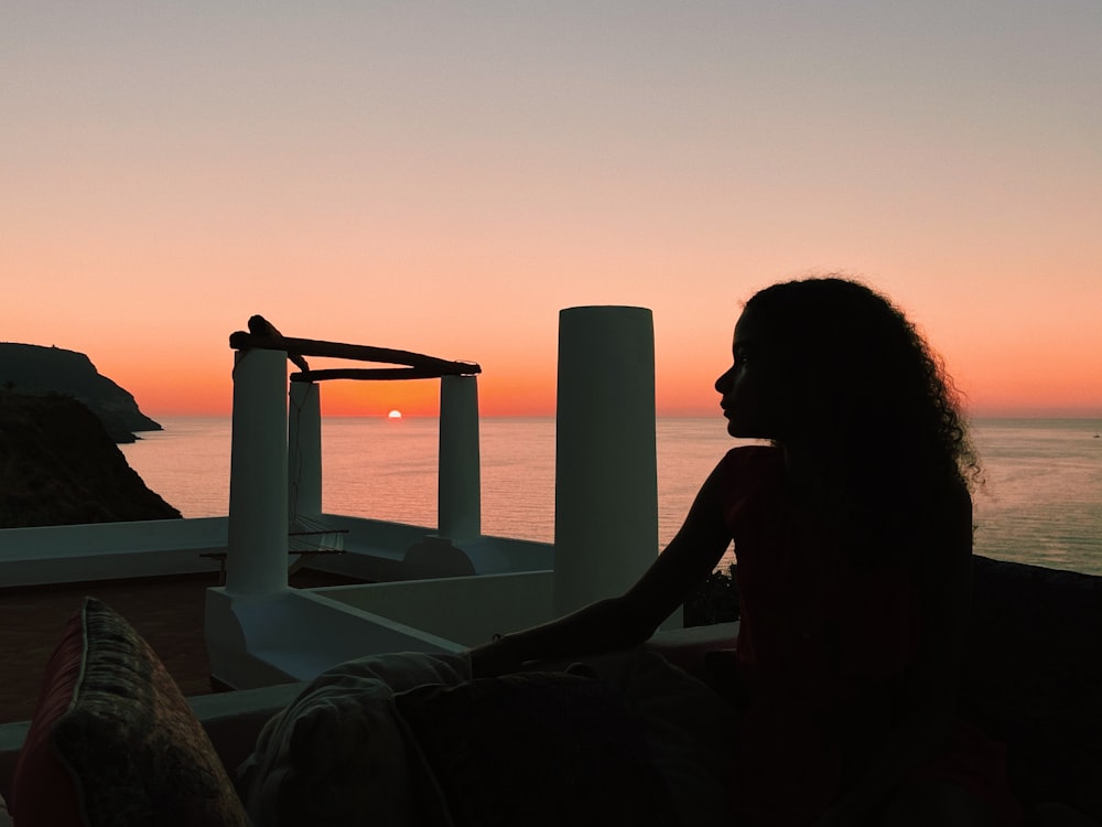 silhouette of woman sitting on bed near window during daytime