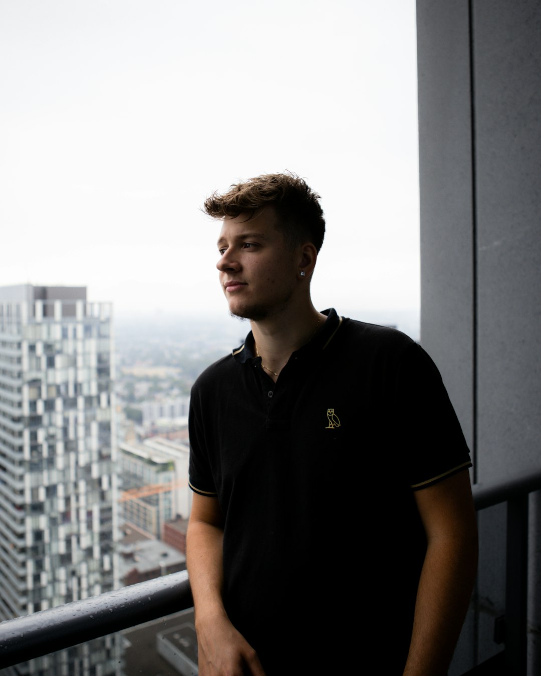man in black polo shirt standing near window during daytime
