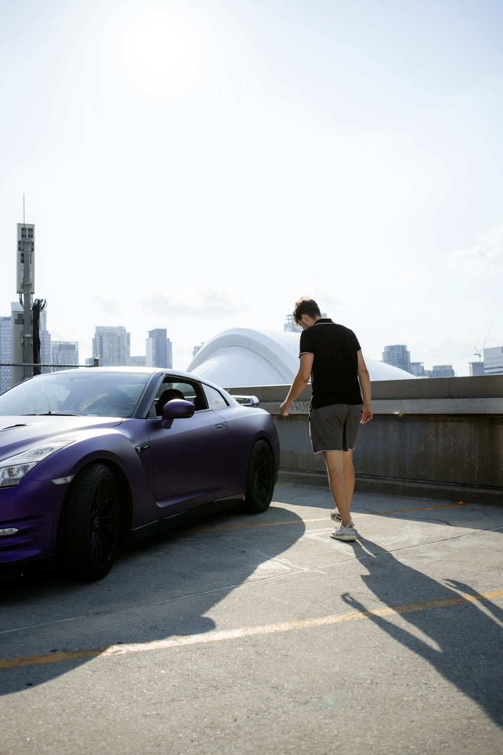 woman in black shirt and black shorts standing beside purple car during daytime