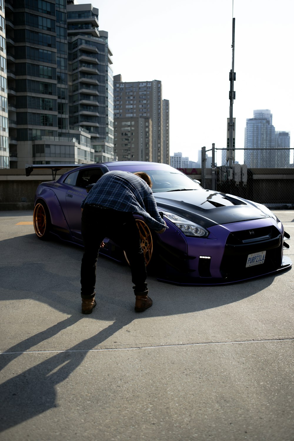 man in black jacket and black pants standing beside black bmw m 3