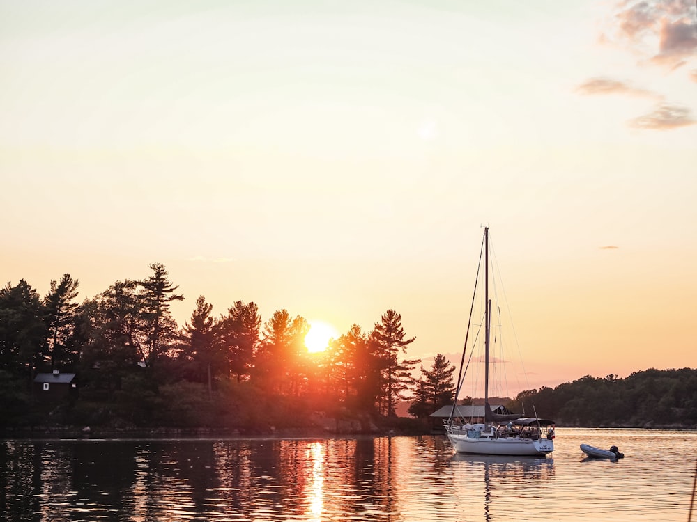 white and blue boat on water during sunset