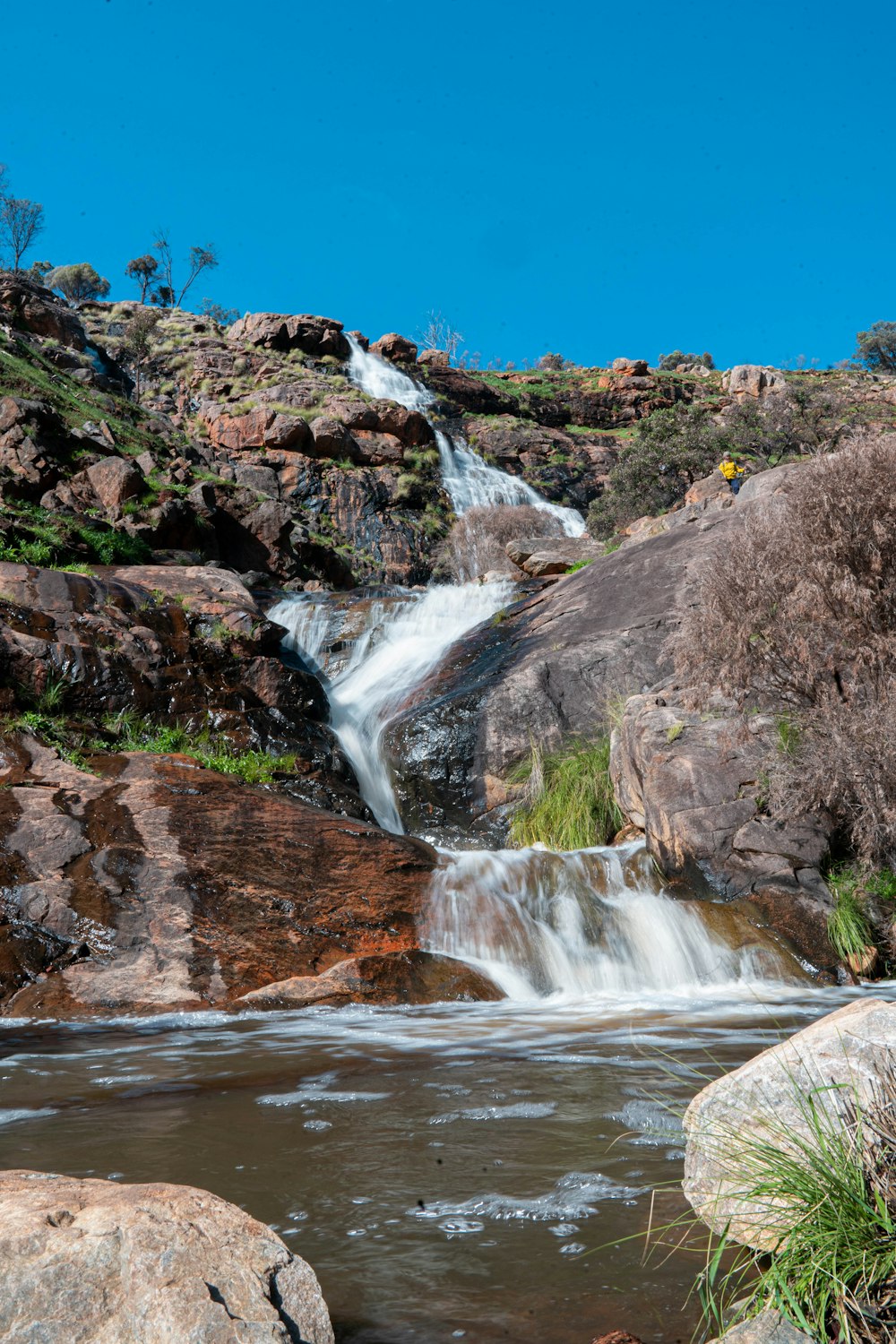 water falls on brown rocky mountain under blue sky during daytime