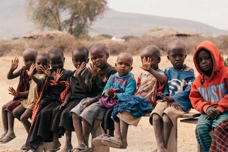 children sitting on brown sand during daytime