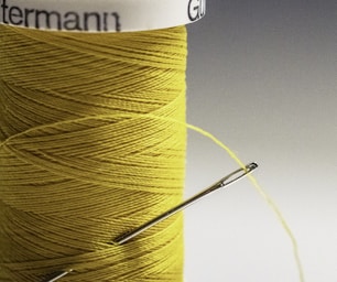 macro photography,how to photograph threading a needle; yellow thread on white paper