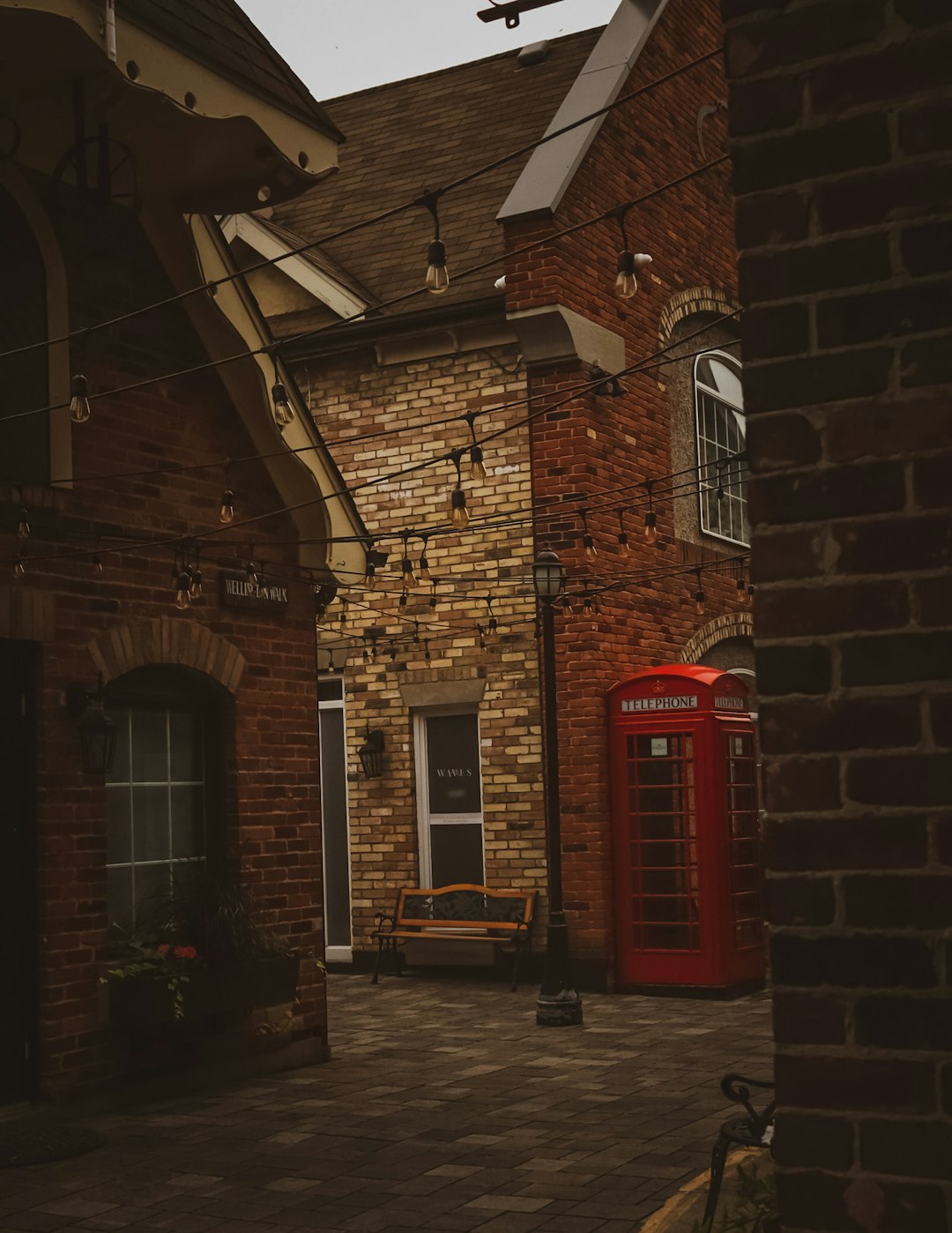 red telephone booth beside brown brick building