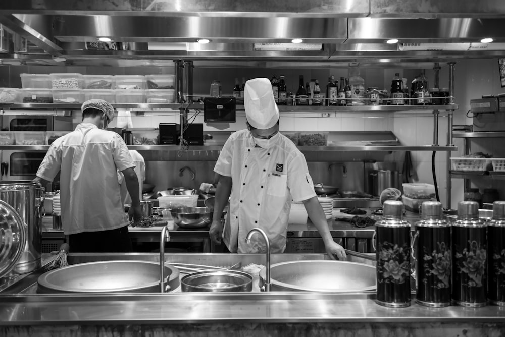 hombre con uniforme de chef blanco de pie frente al mostrador de la cocina