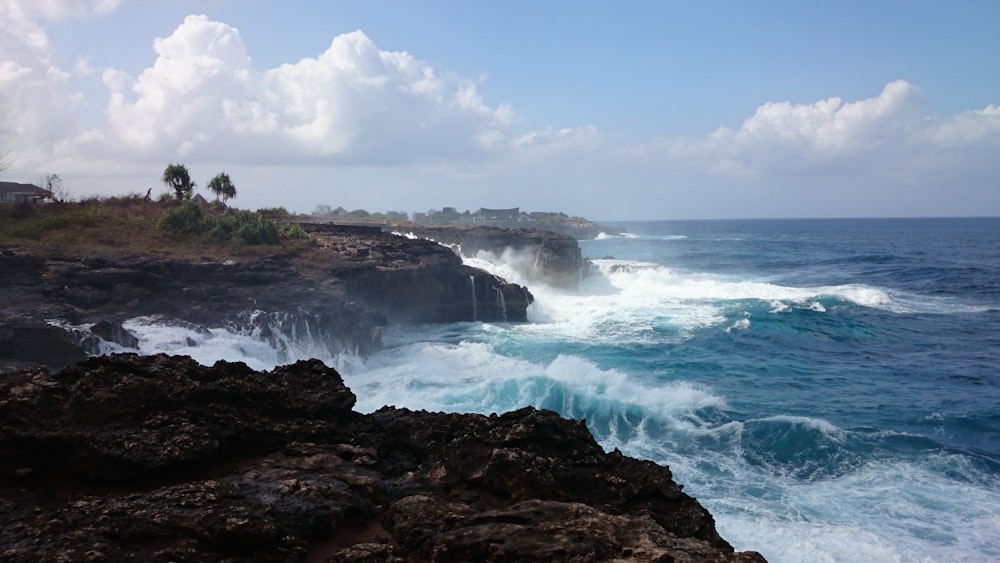 ocean waves crashing on brown rocky shore during daytime