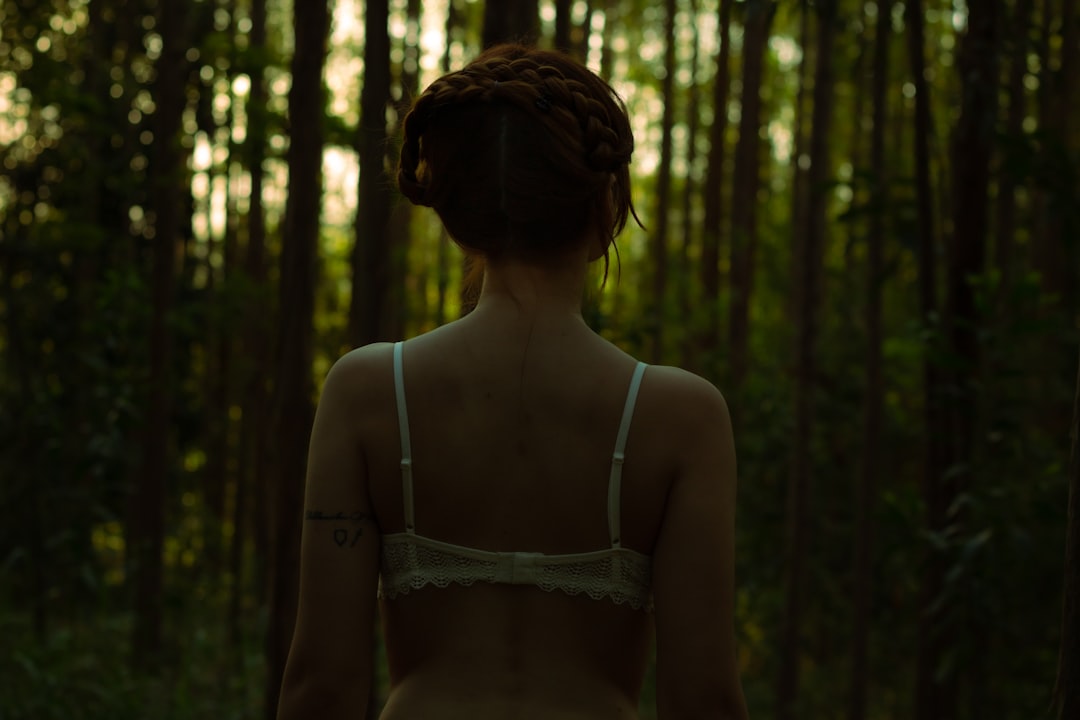 woman in white brassiere standing in forest during daytime