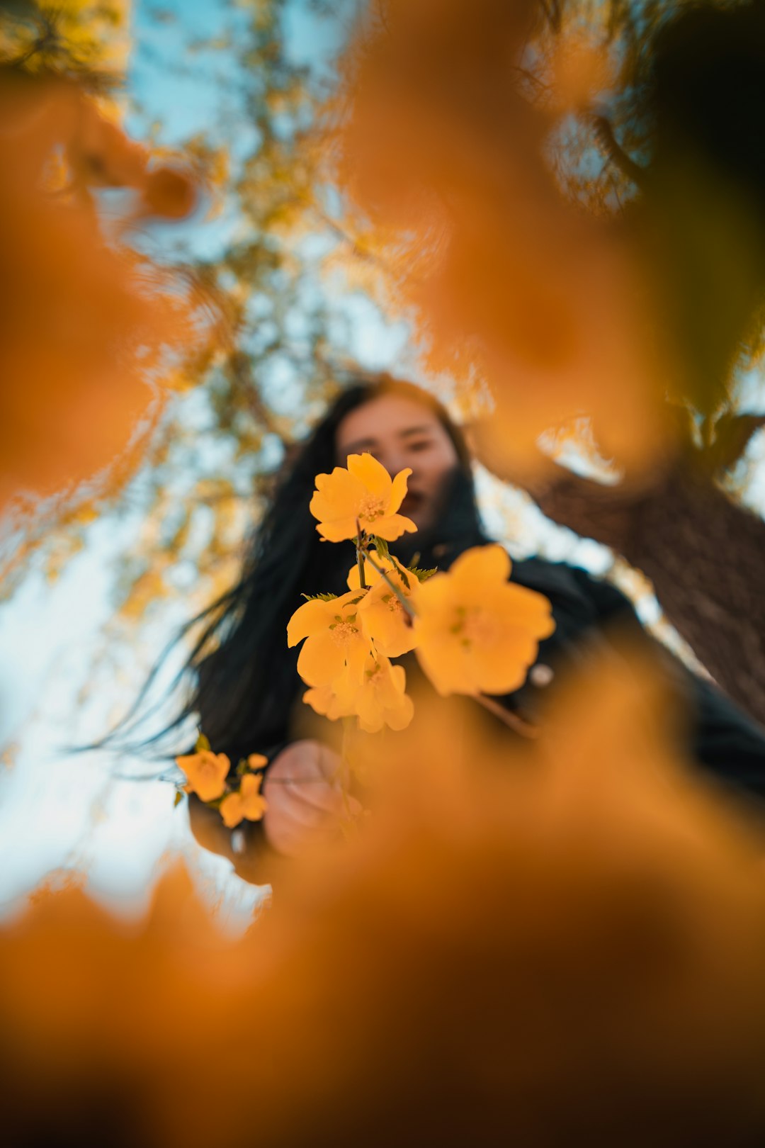 woman in black and white shirt holding yellow flower